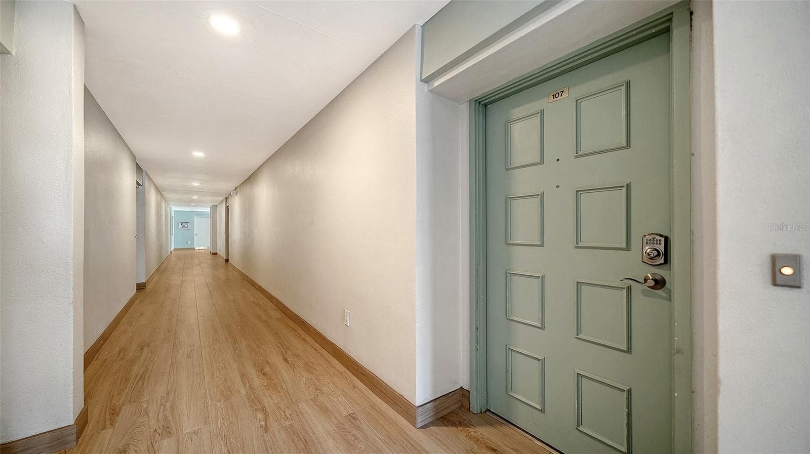 Front door of Unit #107. Interior hallway of building features new 2025 tiled floors. - 101 WHISPERING SANDS DR #107, SARASOTA