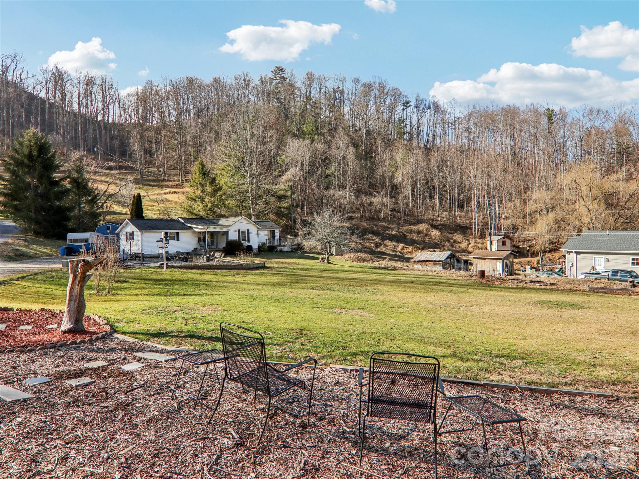 Expansive, gently sloping front yard with usable open space, mature trees, and a peaceful rural setting, offering views across the property toward the home and surrounding wooded hillsides. - Weaverville