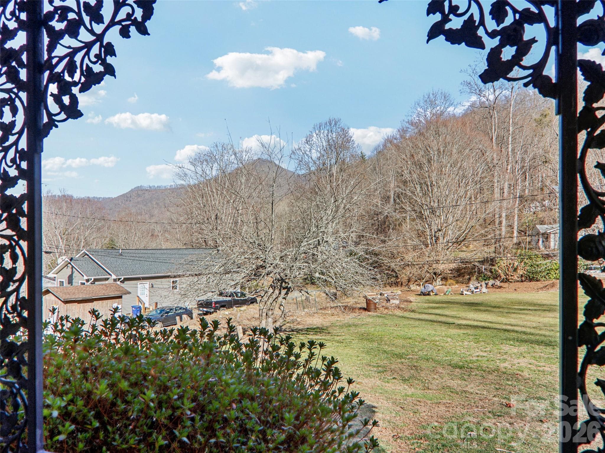 Peaceful front porch view overlooking the expansive front yard and surrounding natural landscape, with mountain and wooded hillside views providing a tranquil setting to enjoy the outdoors. - 7 Landon Mountain Lane, Weaverville