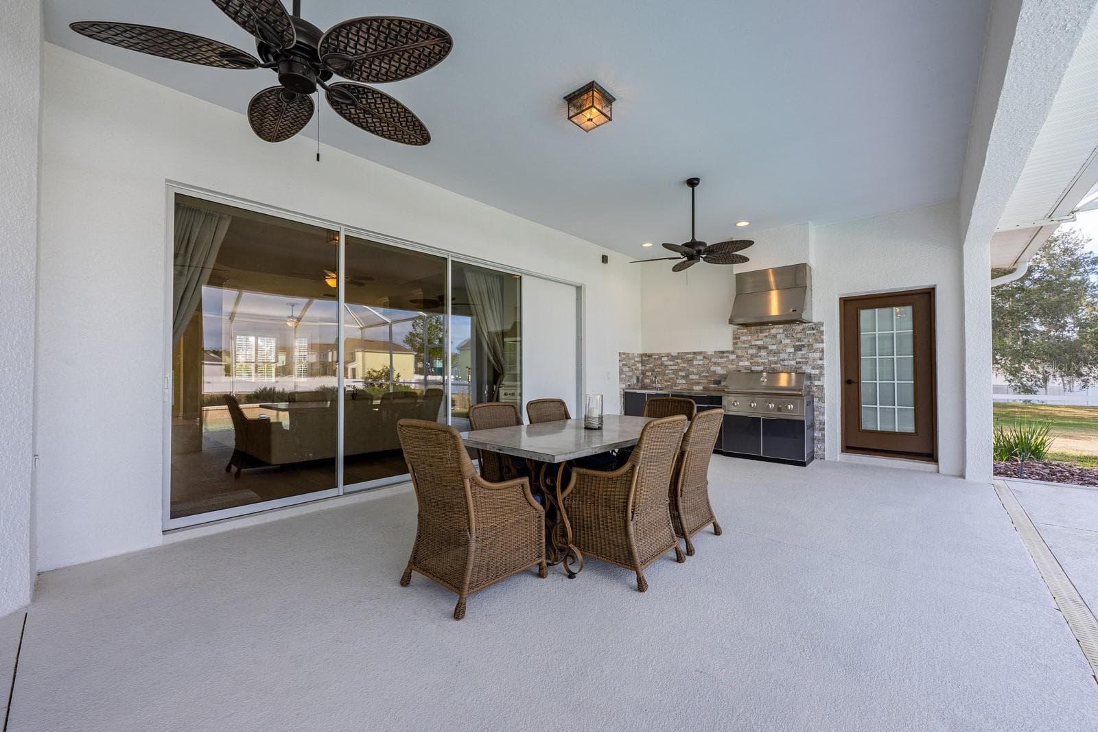 Outdoor living truly shines here - an expansive lanai with a BRAND NEW OUTDOOR KITCHEN – complete with stone finishes, stainless hood, gas range, sink, and built-in beverage refrigerator – overlooks the HEATED POOL and seemingly endless backyard. - 5092 NE 81ST BLVD, WILDWOOD