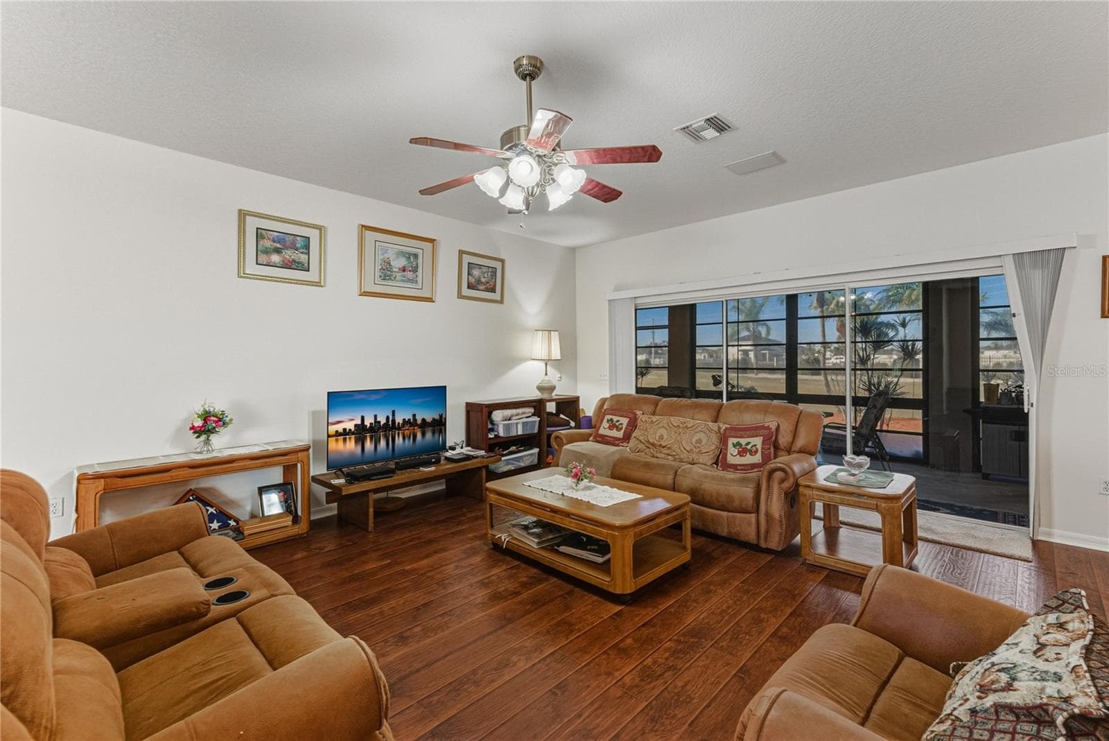 The living room has a triple slider that opens to the covered, enclosed, and screened lanai. - 4360 ASHTON CLUB DR, LAKE WALES