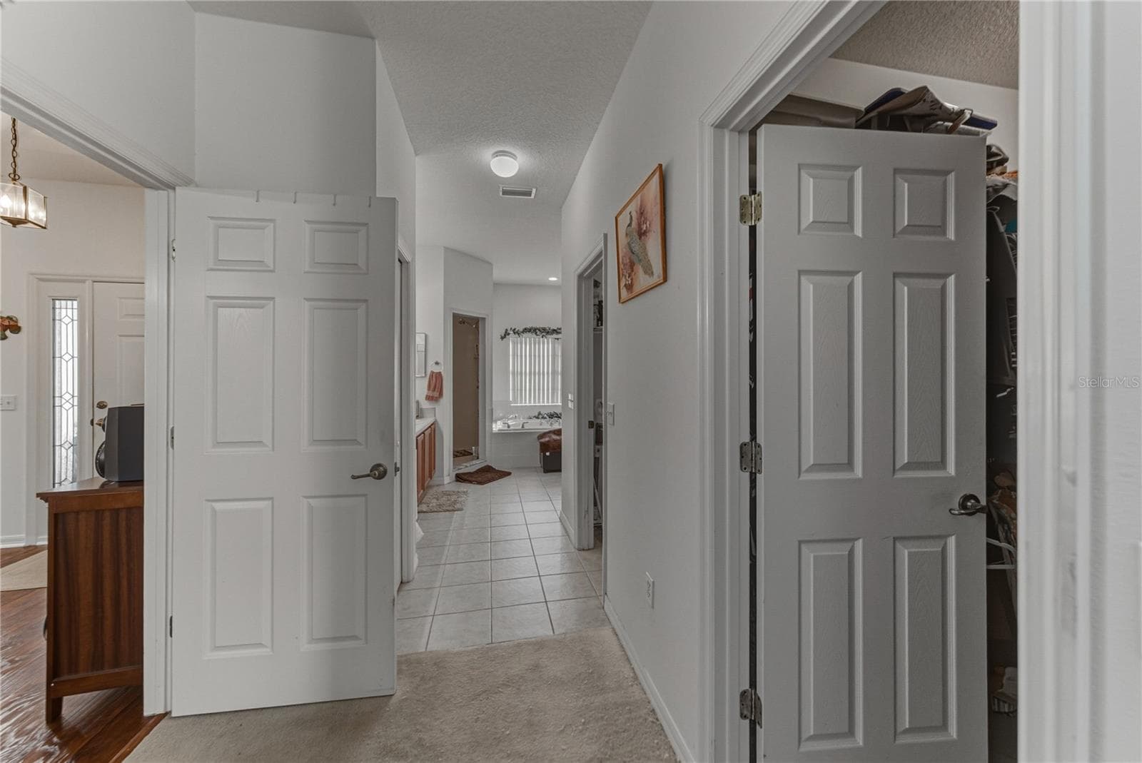 The hallway that connects the primary bedroom with the primary bath has the large walk-in closet and the inside laundry room. - 4360 ASHTON CLUB DR, LAKE WALES