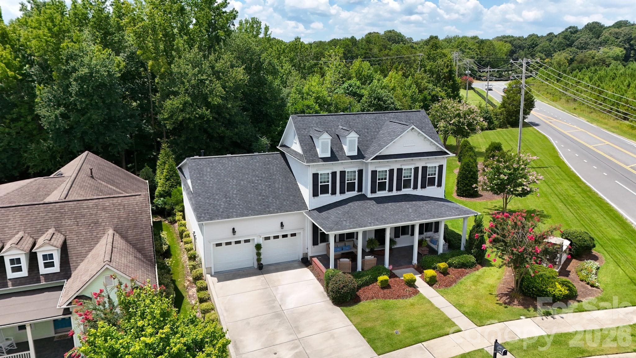 Manicured corner lot in a tree-lined subdivision, with professionally landscaped yard, neatly trimmed hedges, flowering crepe myrtles, and sculpted mulch beds. - 2702 Arsdale Road, Waxhaw