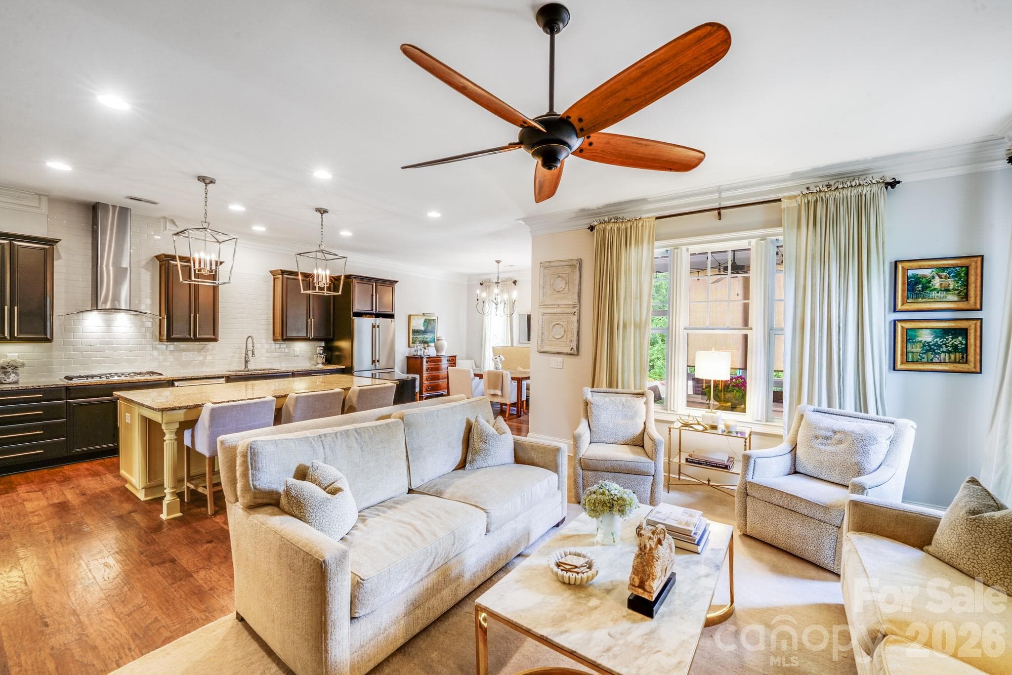 Great room features a large picture window dressed in soft drapery, offering views of the screened porch and flooding the space with natural light - 2702 Arsdale Road, Waxhaw
