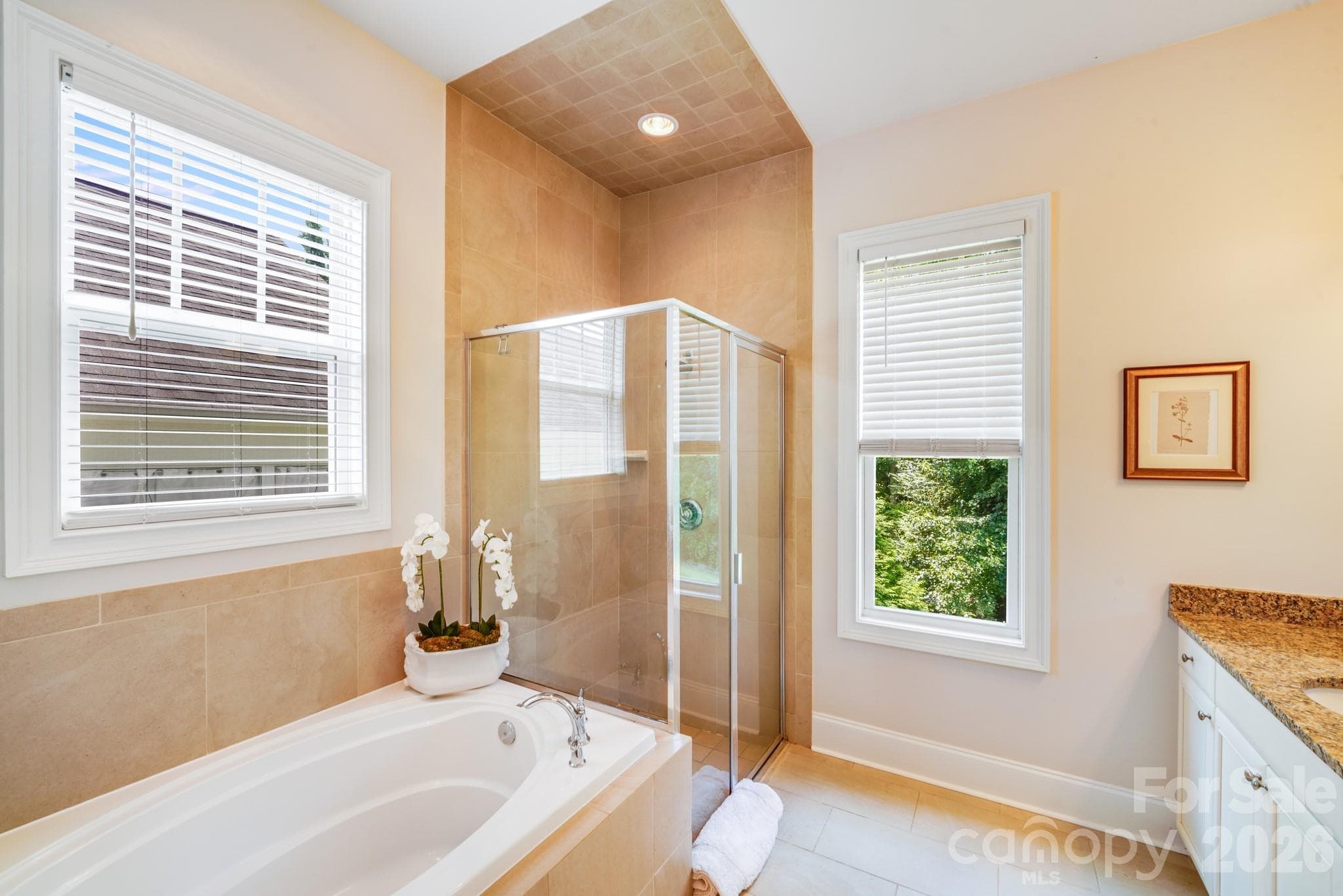 Frameless glass walk-in shower and a large soaking tub, neutral tile flooring and floor to ceiling tile surround for a timeless, clean aesthetic - 2702 Arsdale Road, Waxhaw