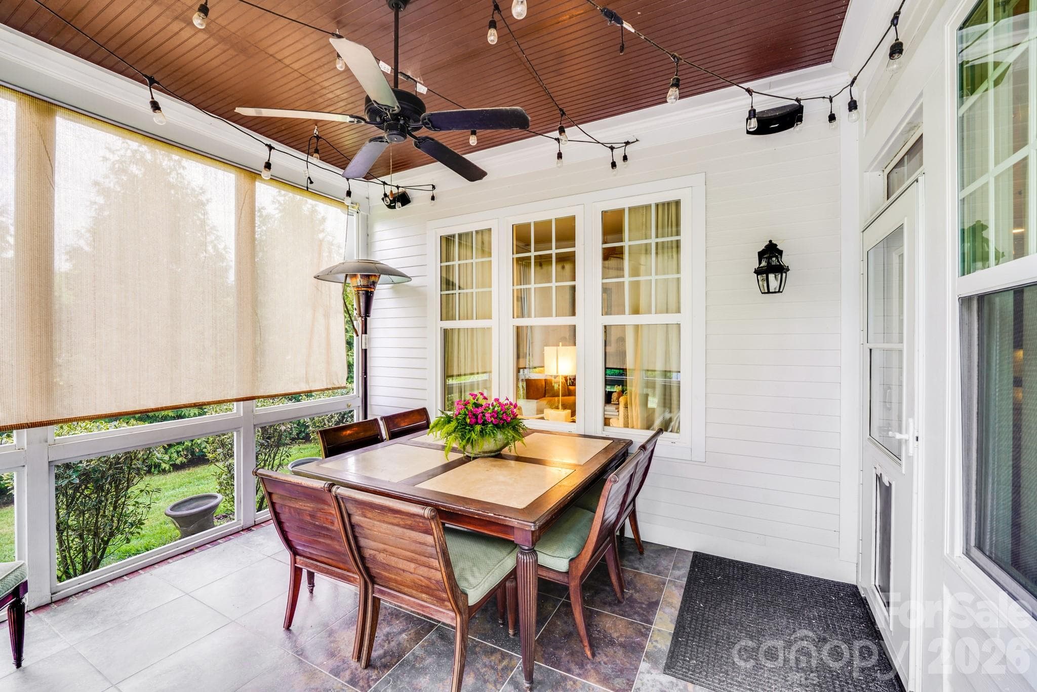 Elegant screened porch, complete with a rich wood-paneled ceiling, string lights, ceiling fan and roll-down shades - 2702 Arsdale Road, Waxhaw
