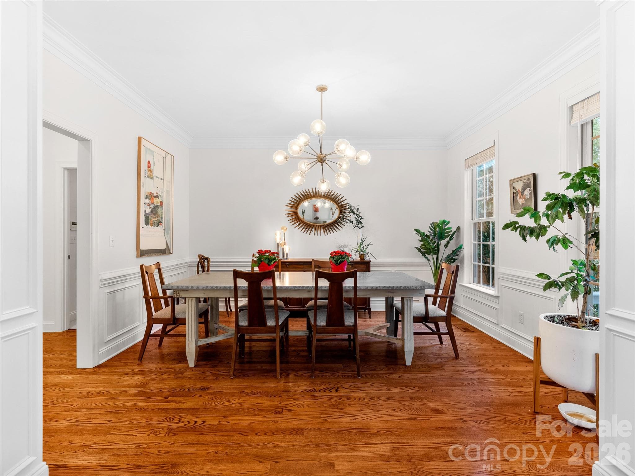 Highlighting hardwood floors and decorative wainscoting, the dining room is filled with natural light, offering both charm and a welcoming ambiance. - Asheville