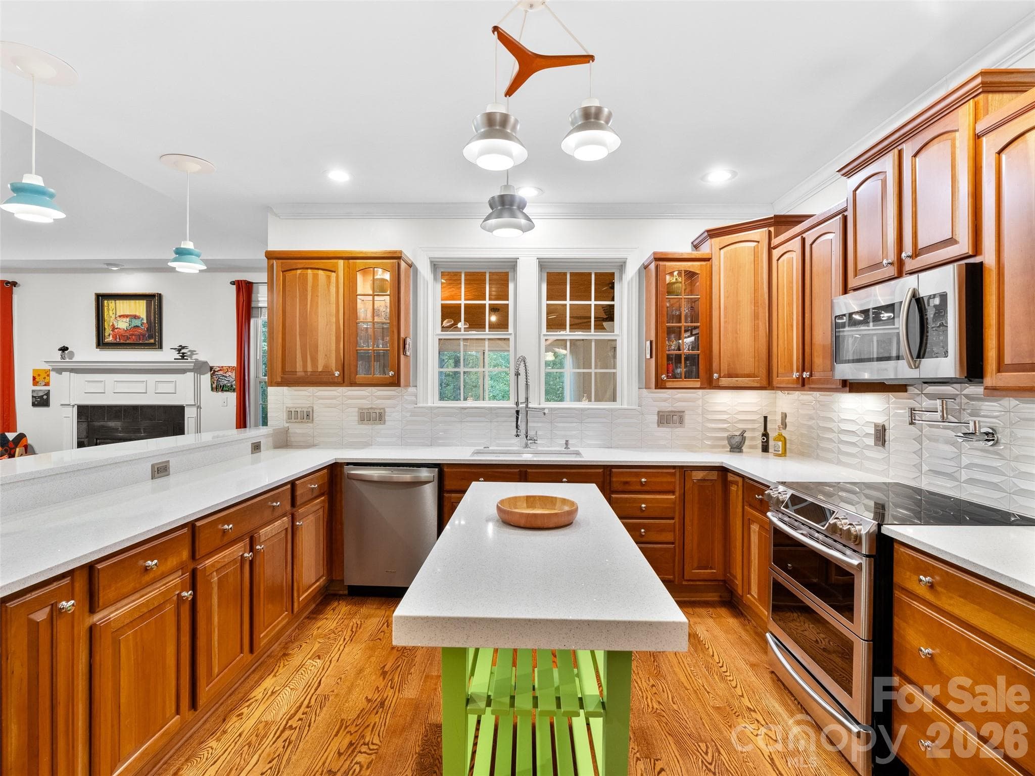 Bright and open, the kitchen combines hardwood floors with contemporary stainless steel appliances and eye-catching backsplash, creating a welcoming space for cooking and gathering. - Asheville