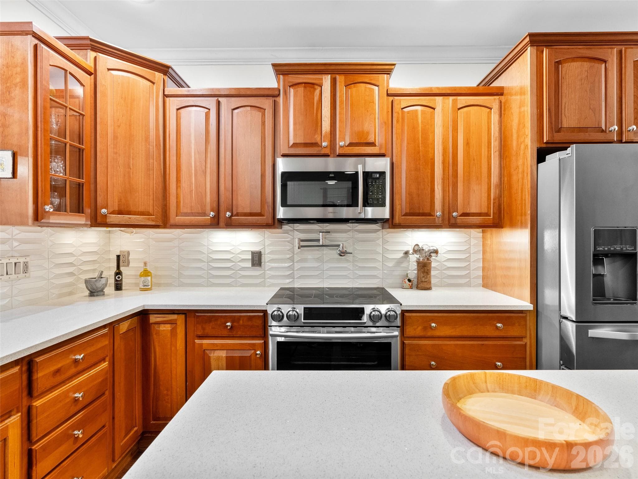 This close-up view highlights the kitchen's custom cabinetry, sleek stainless steel appliances, and a striking backsplash, blending style and practicality in a beautifully designed space. - Asheville