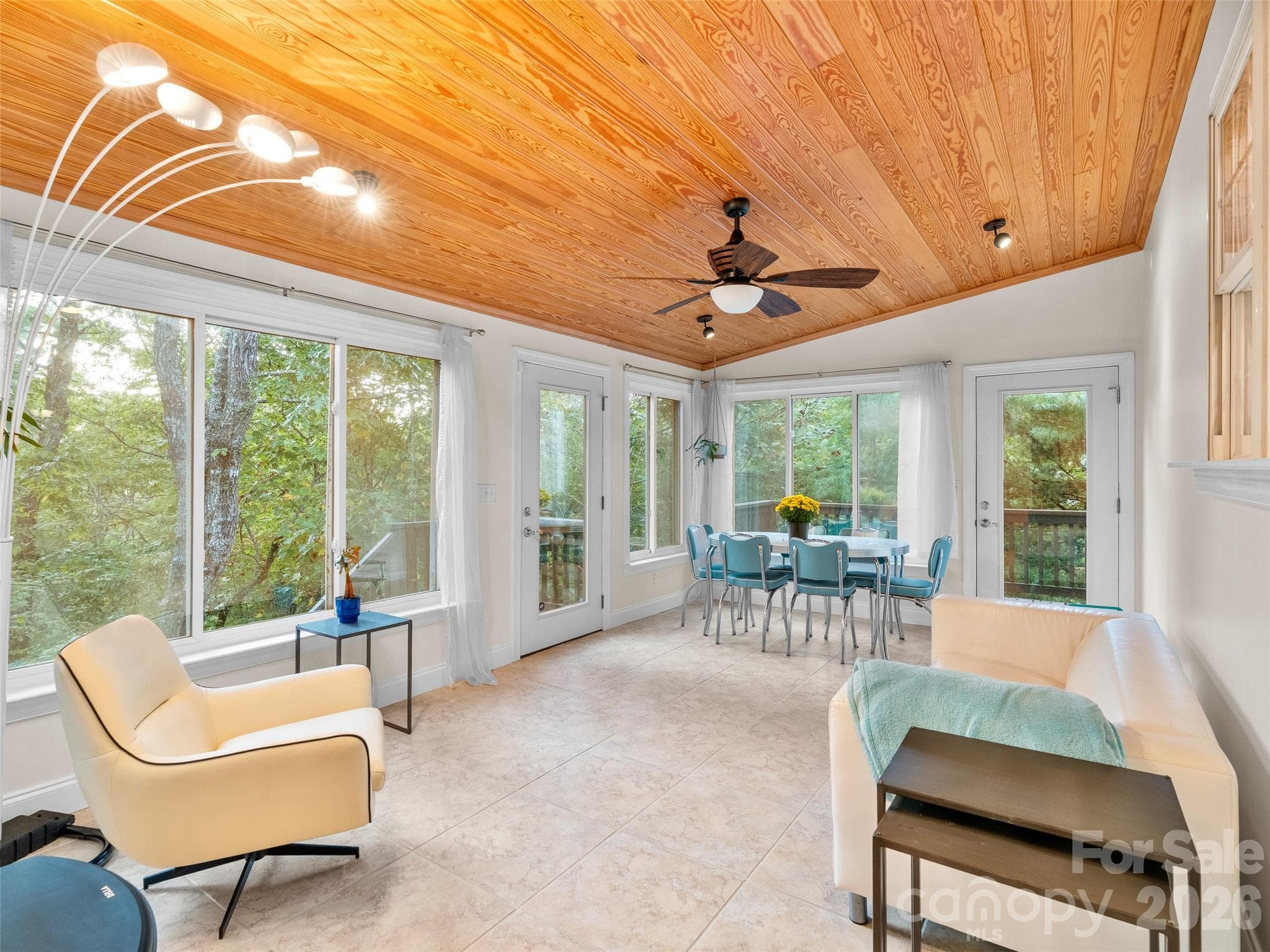 This sun-filled room features windows on every wall, a warm wood ceiling, and a tile floor, with direct access to the deck and outdoor spaces-perfect for relaxing or entertaining - Asheville