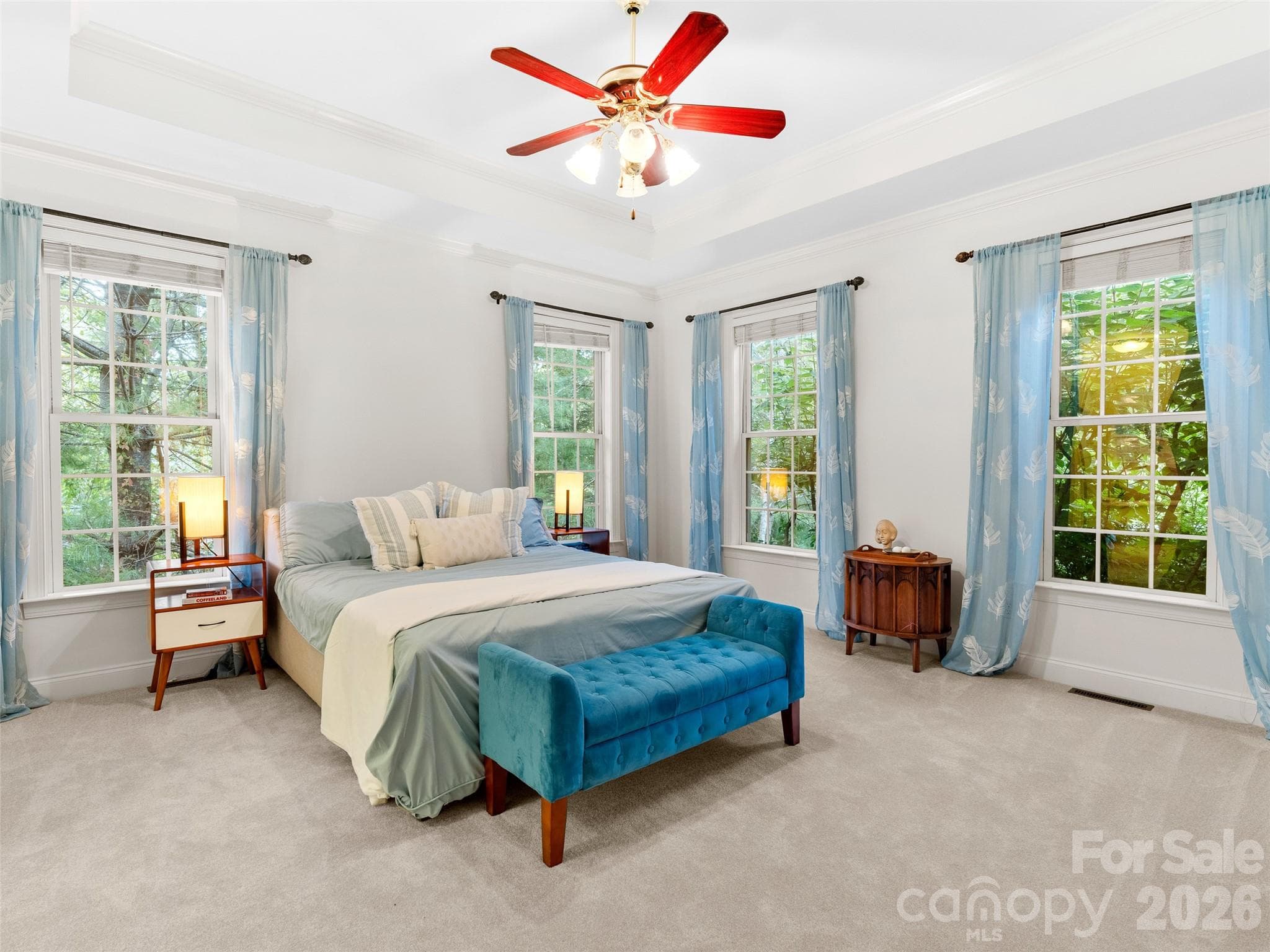 This main-level master suite features coffered ceilings and ample windows that frame serene views of nature, creating a peaceful retreat with natural light. - Asheville