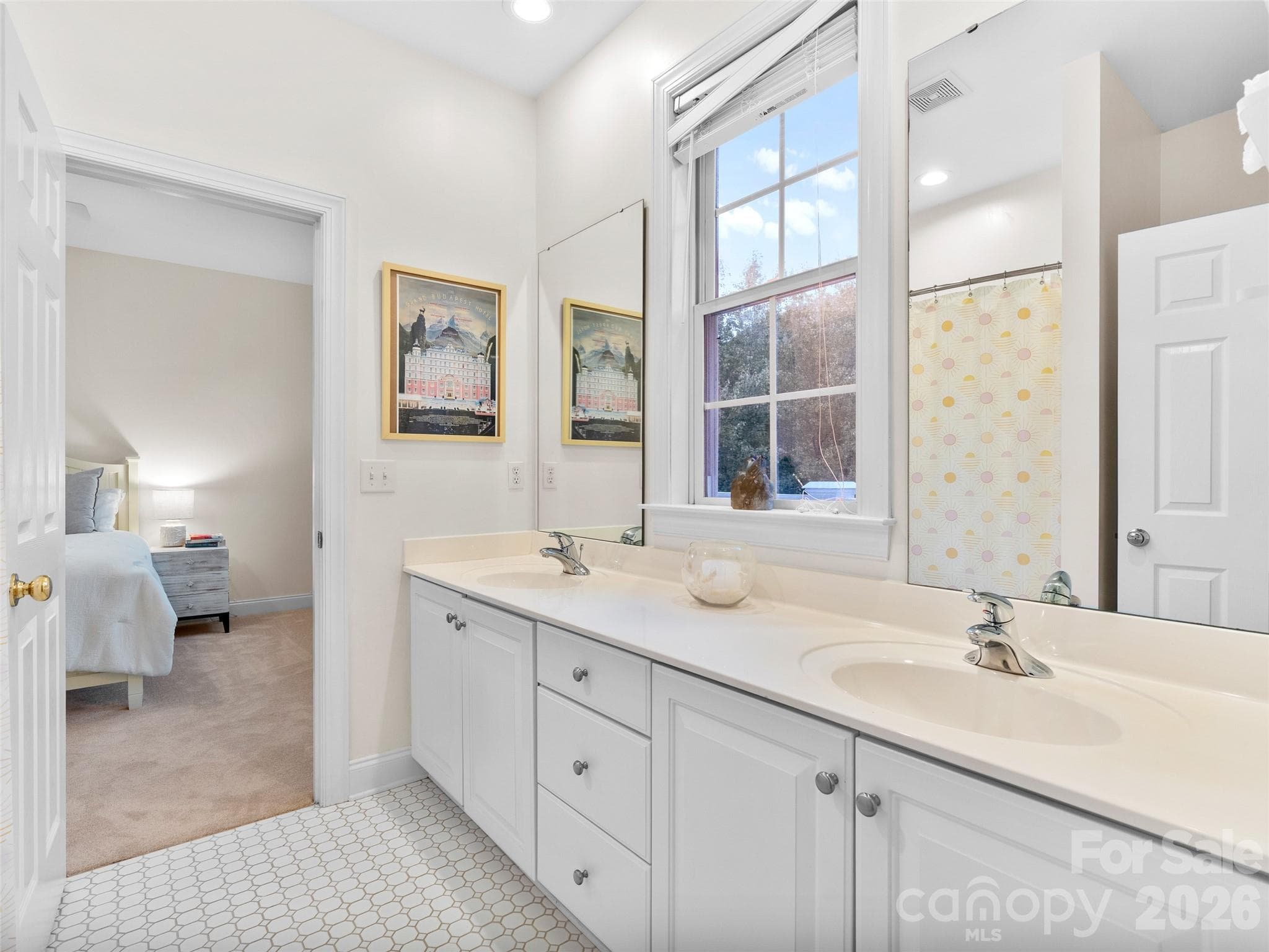 A beautifully appointed shared bathroom with tiled flooring, dual vanities, and a window overlooking nature, provides both style and functionality for family living. - Asheville