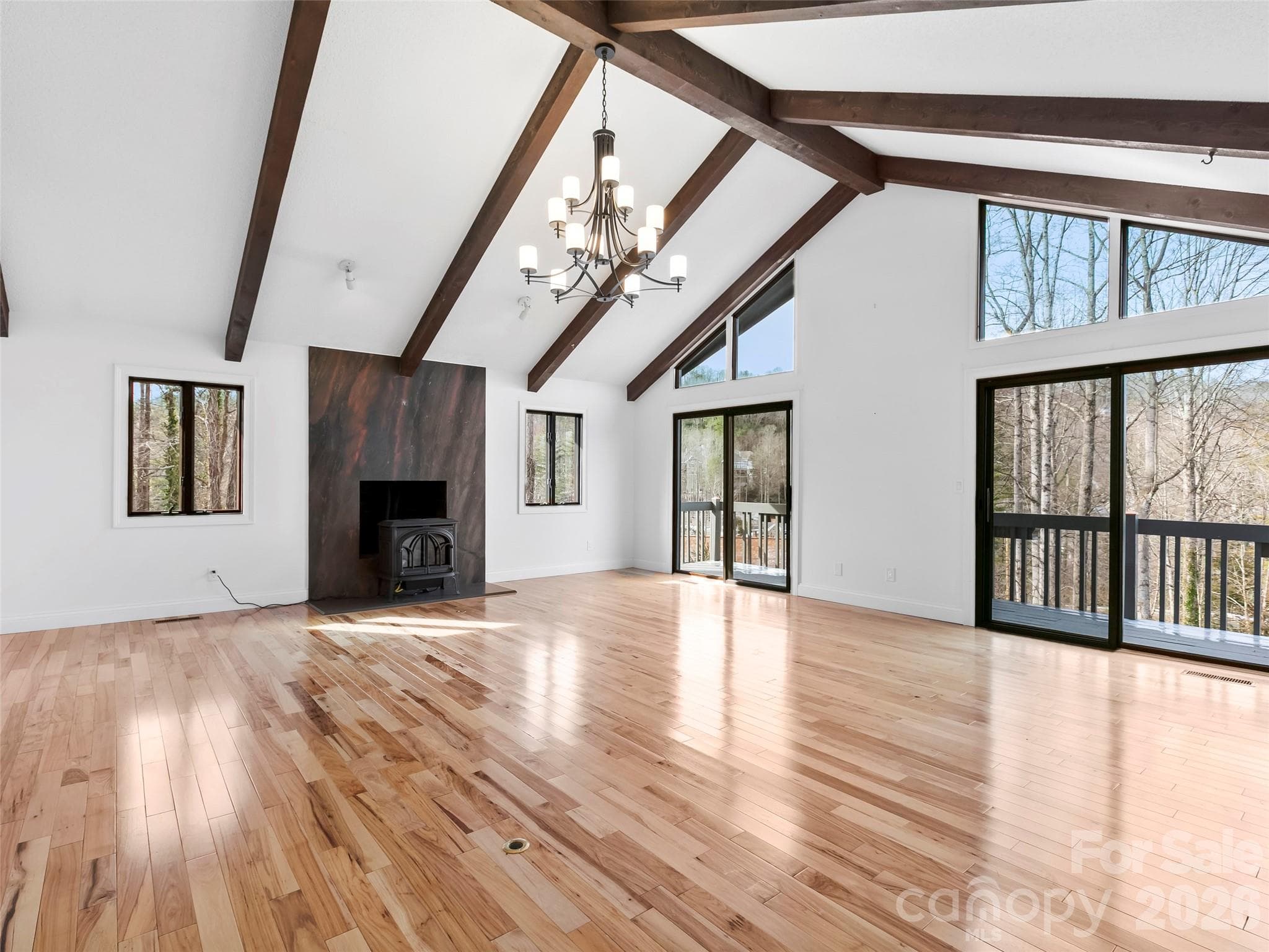 Designed for comfort and connection, the Great Room features vaulted character, wood beams, a cozy Jøtul stove, and a wet bar perfect for hosting family and friends. - 2731 Miller Lane, Hendersonville