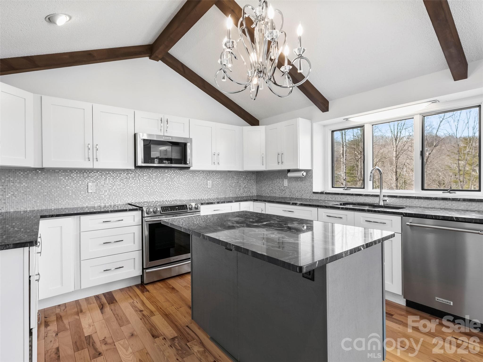 The kitchen island and exposed wood beams add warmth and character, creating an inviting space for gathering. - 2731 Miller Lane, Hendersonville