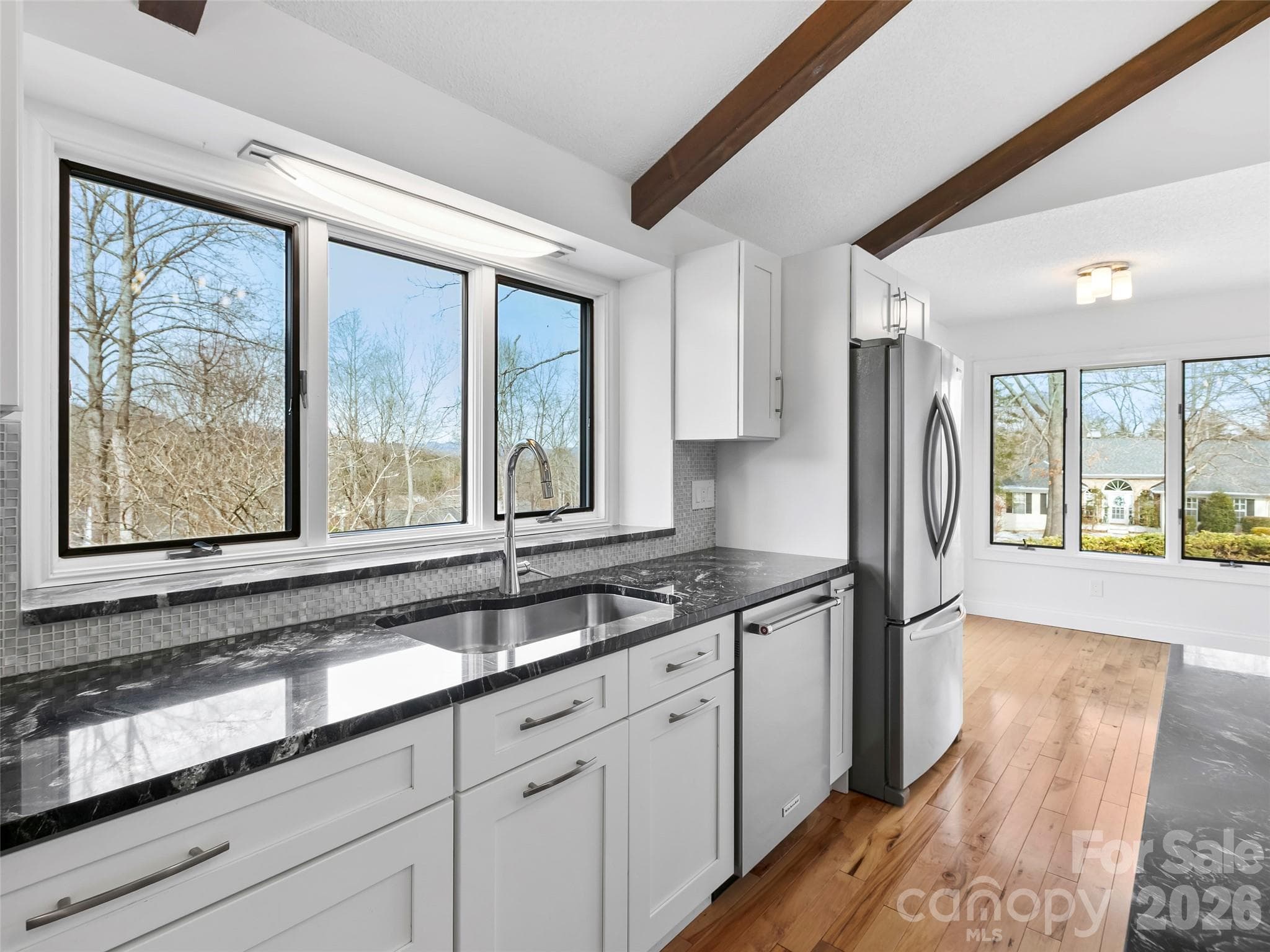 Abundant windows bring in beautiful natural light throughout the home, enhancing the welcoming atmosphere and bright, airy feel of the space. The kitchen flows effortlessly into the cozy breakfast area, creating the perfect spot for casual dining, conversation, and enjoying the surrounding views. - 2731 Miller Lane, Hendersonville