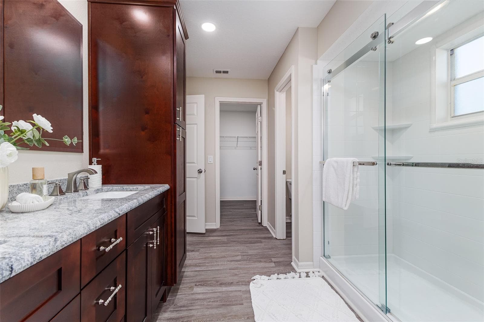 En Suite Primary Bath with Shower, dual sinks, stone countertops, plenty of storage, great lighting, and walk-in-closet, and water-closet toilet room. - 411 EDGEWATER DR, POLK CITY