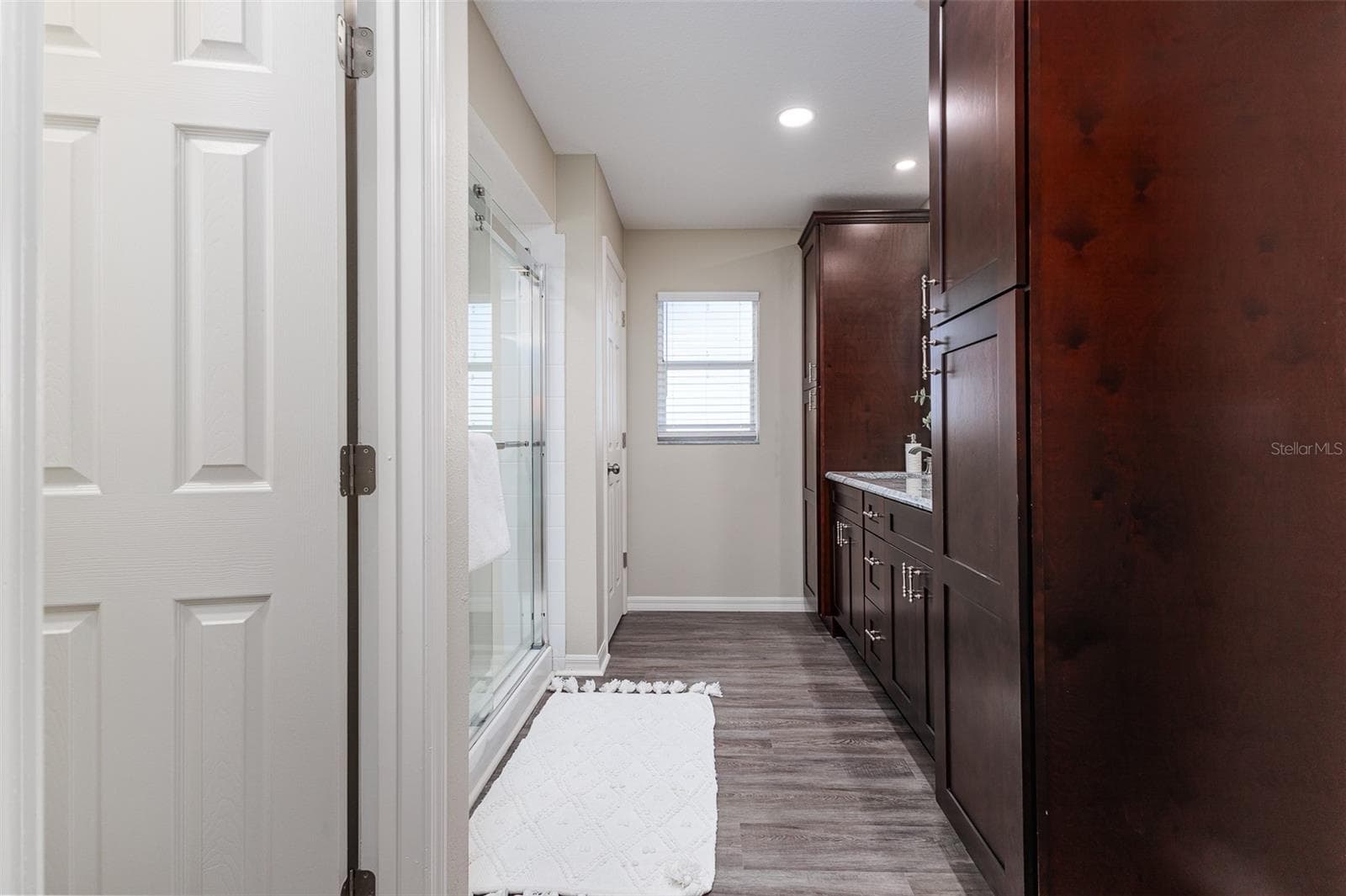 En Suite Primary Bath with Shower, dual sinks, stone countertops, plenty of storage, great lighting, and walk-in-closet, and water-closet toilet room. - 411 EDGEWATER DR, POLK CITY
