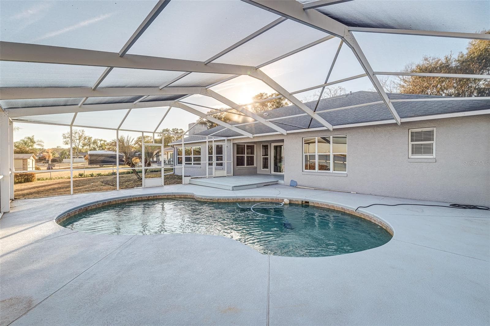 Pool deck featuring covered screened enclosure; expansive views of Lake Agnes - 411 EDGEWATER DR, POLK CITY