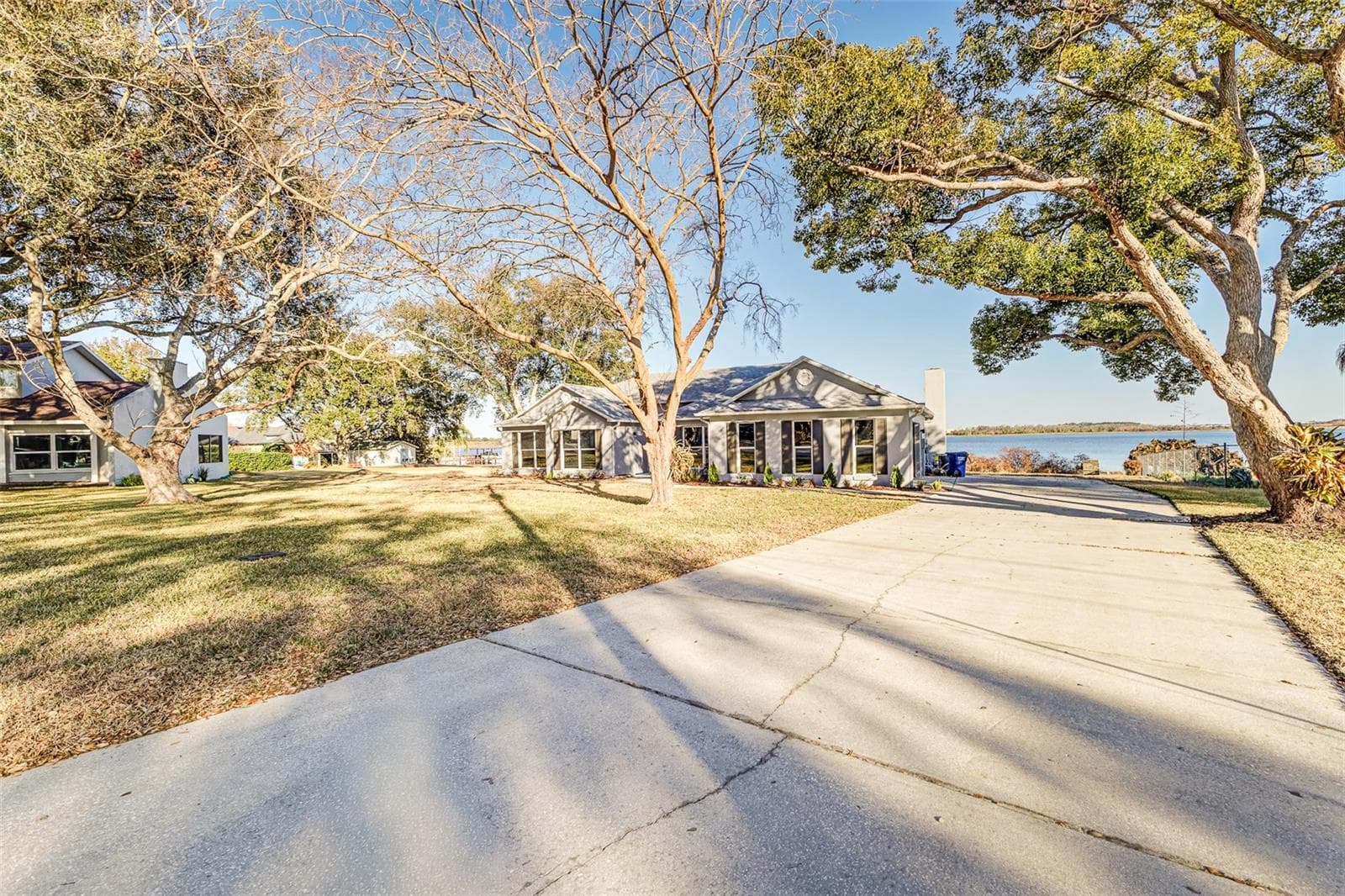 View from Driveway showing plenty of parking spaces, view of Lake Agnes, house, mature trees - 411 EDGEWATER DR, POLK CITY