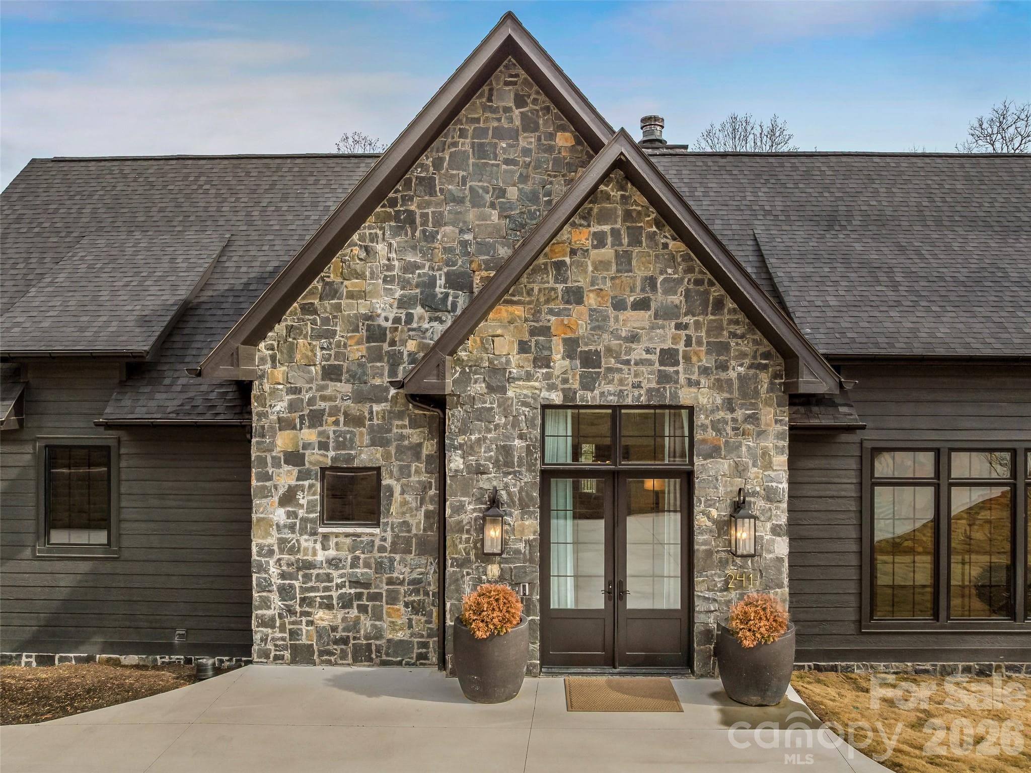 Inviting covered entry with stone façade, glass front door, and architectural gables for striking curb appeal. - 241 Tower Circle, Hendersonville