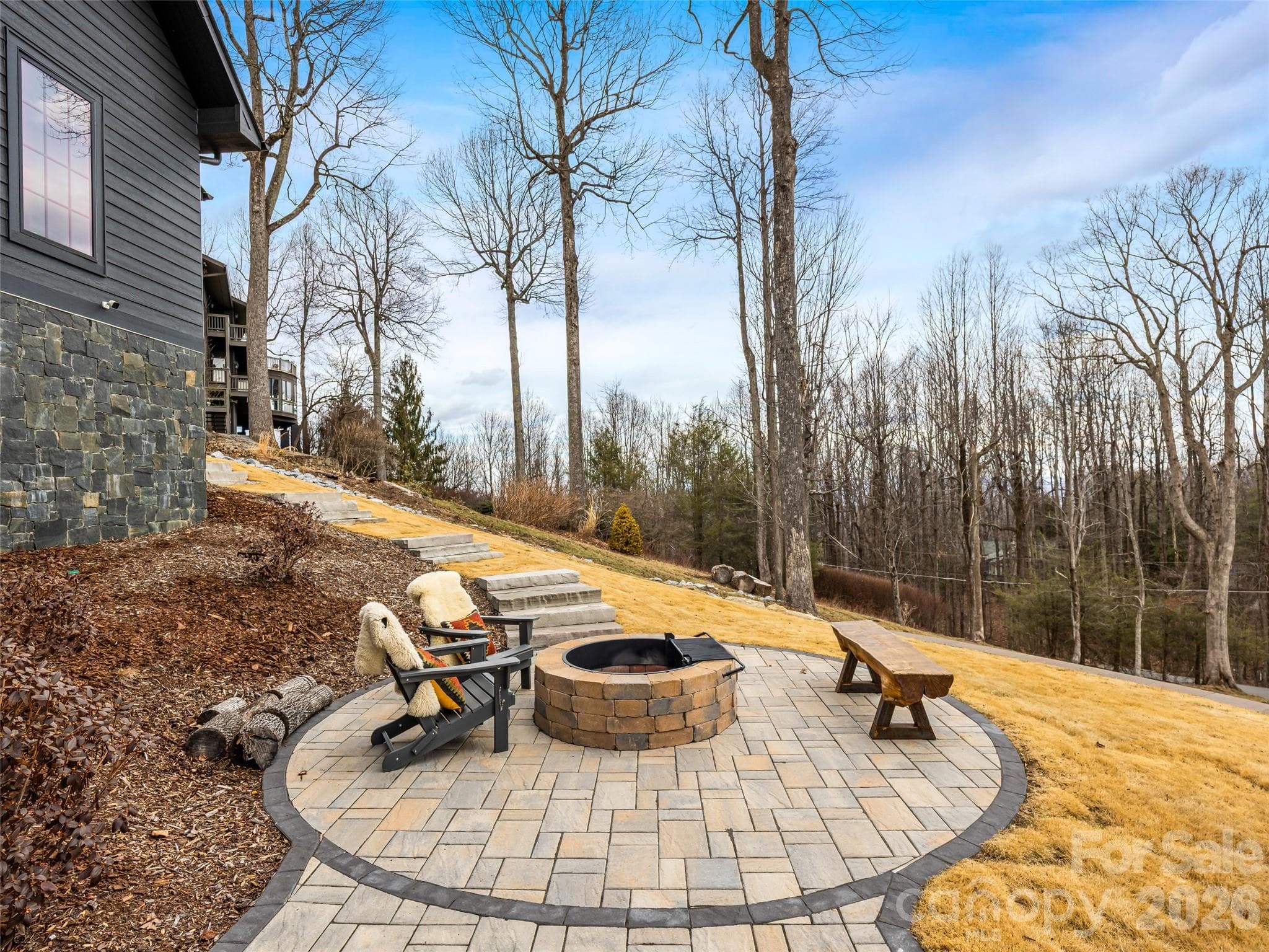 Circular fire pit area with built-in seating and wooded backdrop - 241 Tower Circle, Hendersonville