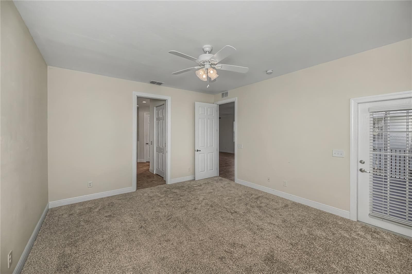 primary ensuite bedroom with door to balcony lanai - new carpet - 25601 HERITAGE LAKE BLVD #46, PUNTA GORDA