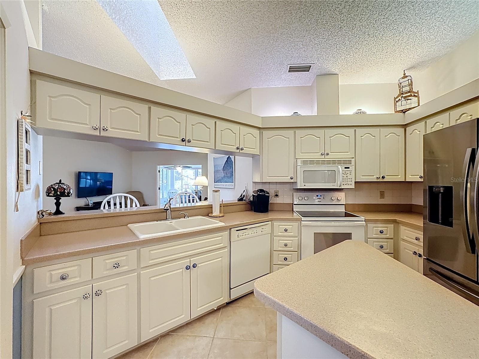 Kitchen with solid surface counters, island, 2024 refrigerator and a skylight for additional natural lighting. - 5611 GARDEN LAKES DR, BRADENTON