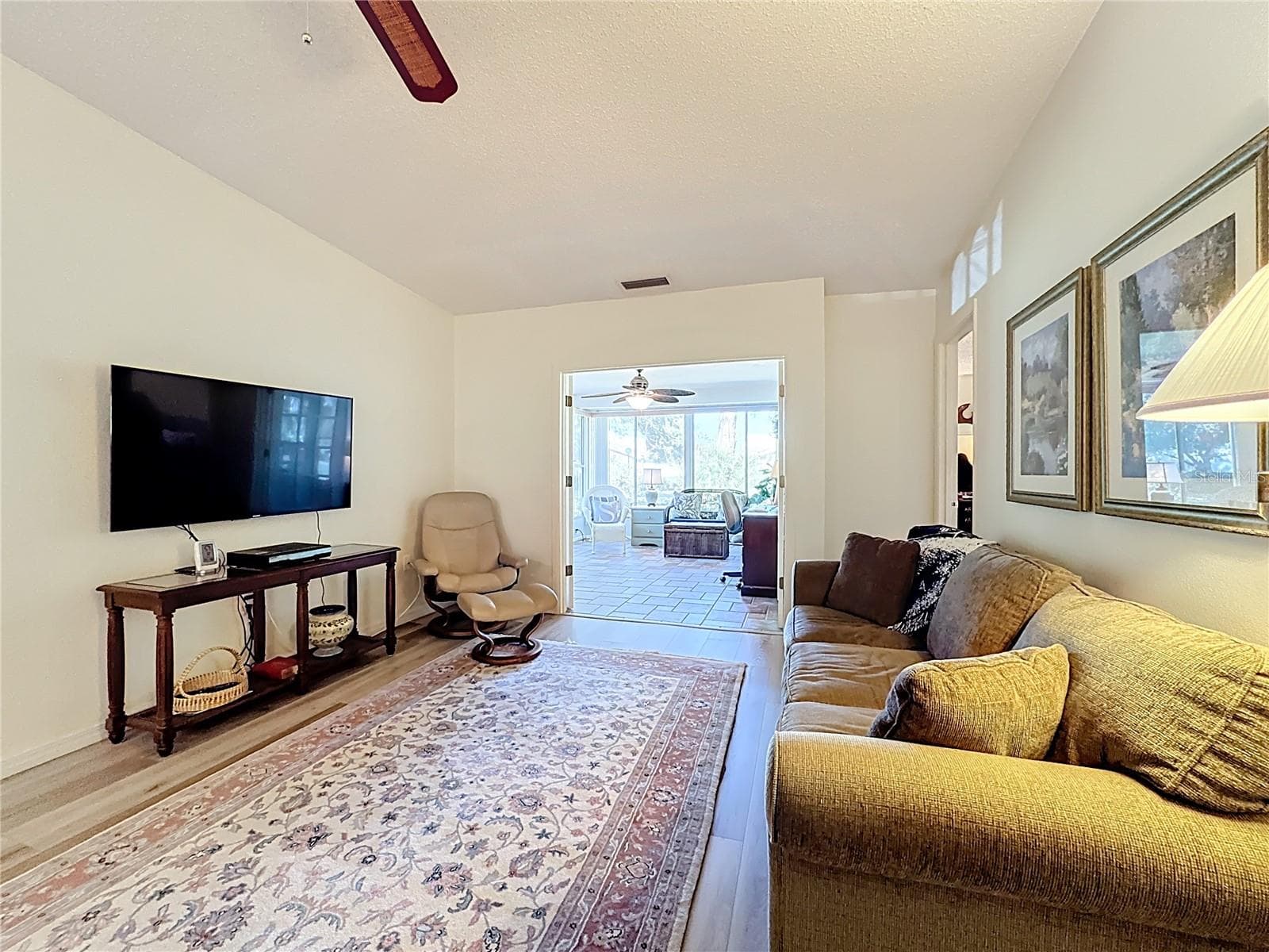 Family room with luxury vinyl flooring and French Doors leading into glass enclosed Florida Room. - 5611 GARDEN LAKES DR, BRADENTON