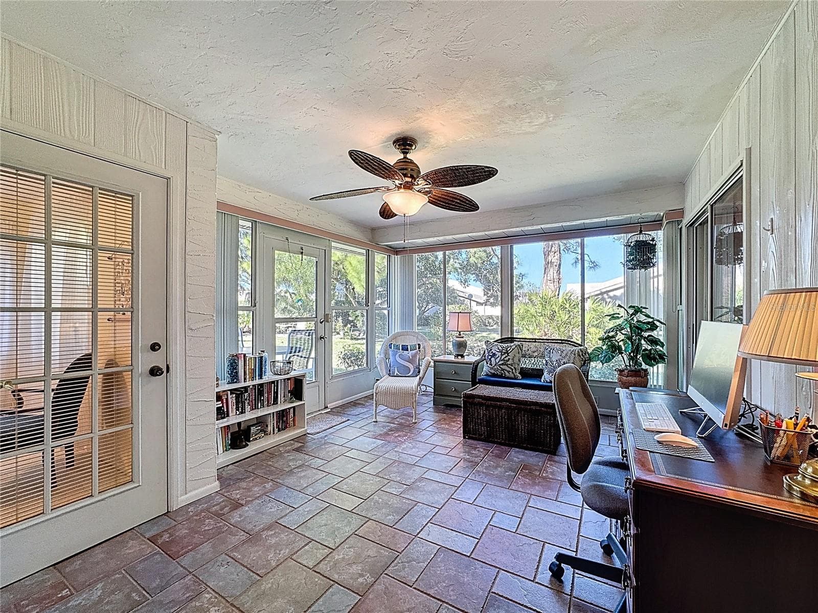 Family room offers accessability from both the guest ensuite and primary bedroom ensuite. Air conditioned, glass enclosed and slate flooring. - 5611 GARDEN LAKES DR, BRADENTON