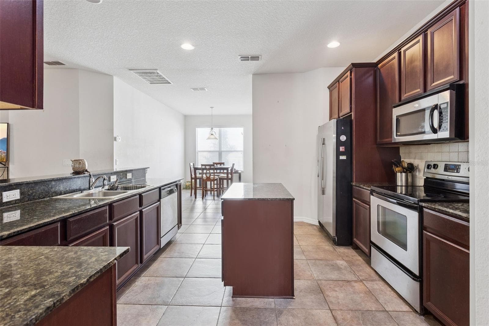 Kitchen featuring granite countertops, center island, and open sightlines to living area - 30337 GIDRAN TER, MOUNT DORA