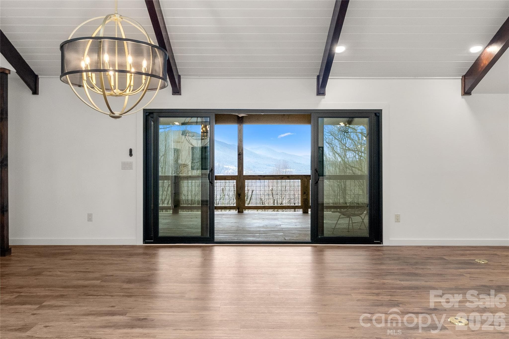 Vaulted great room opens to a covered deck with mountain views. - Waynesville