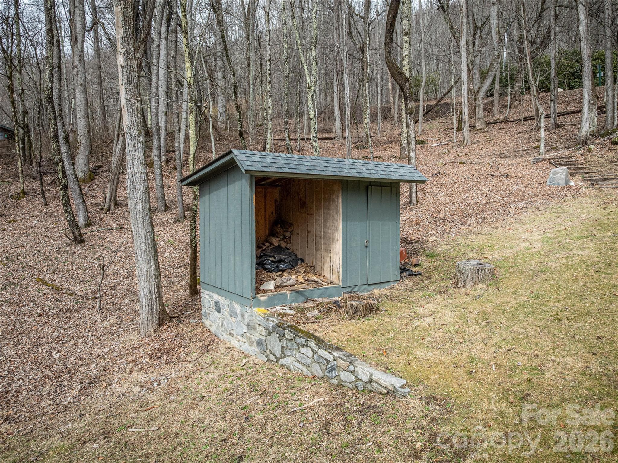 Stone-based accessory structure offering convenient outdoor storage, blending seamlessly with the natural wooded setting. - Waynesville