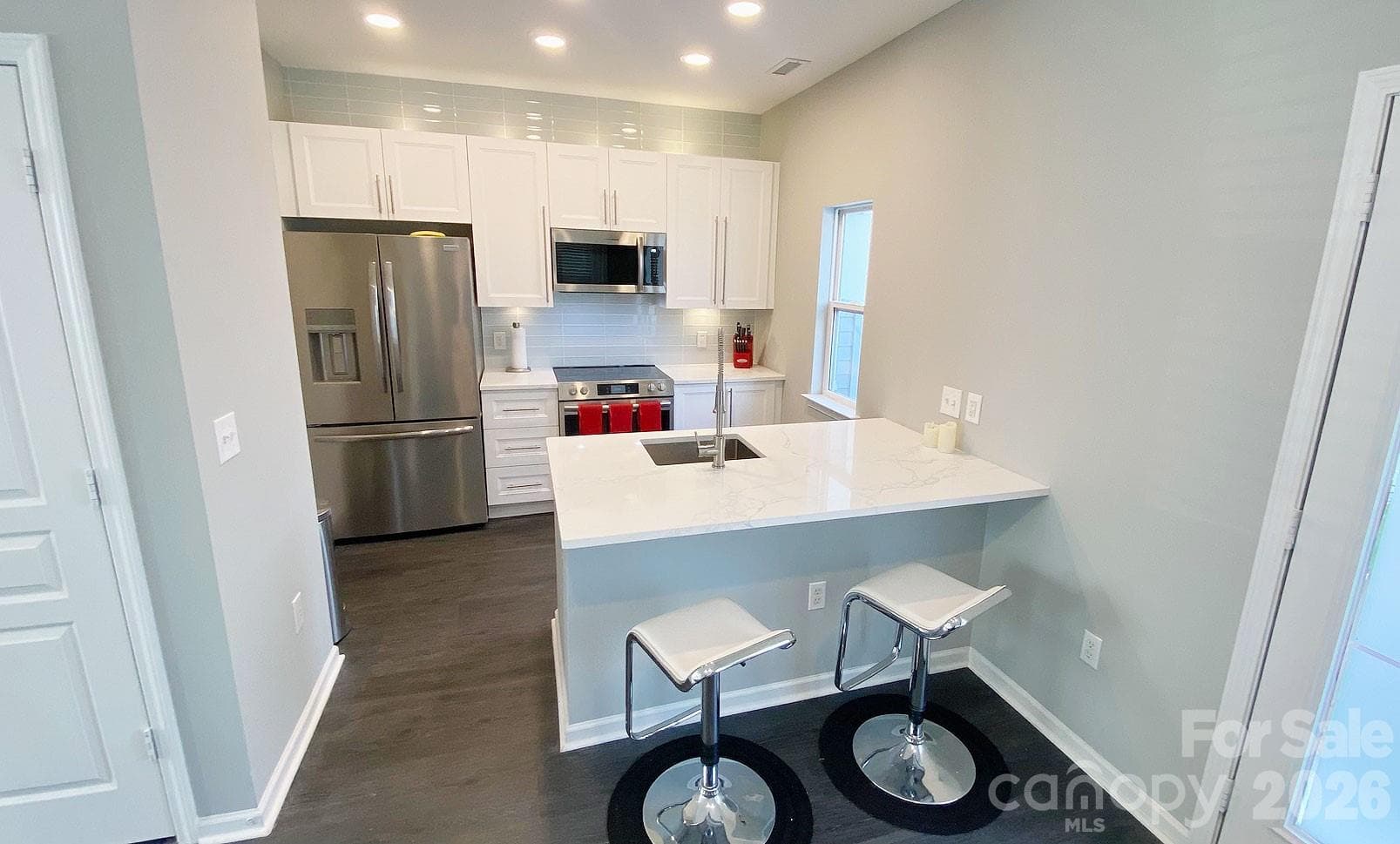 Kitchen has Frigidaire Gallery appliances (all remain) with quartz counters and glass tile backsplash. - Charlotte