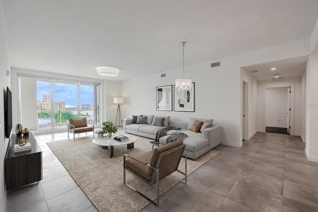 The dining/living room framed by floor to ceiling 'hurricane impact sliders' and a view of the entrance to the primary suite - 920 N OSCEOLA AVE #703, CLEARWATER