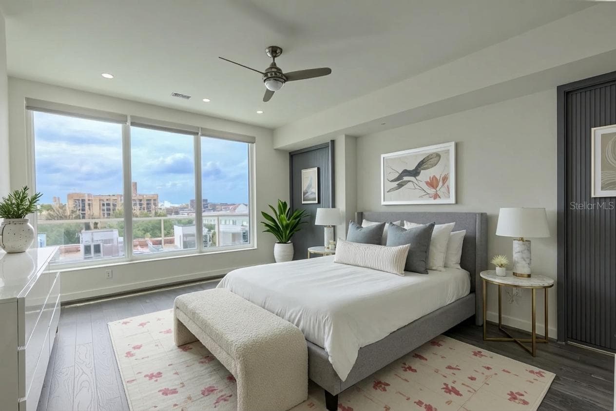 2nd Bedroom: This light-filled bedroom offers sweeping views through a wall of floor-to-ceiling windows that capture both the cityscape and the Intracoastal beyond. Rich hardwood floors and a modern ceiling fan lend a contemporary yet warm feel to the space. - 920 N OSCEOLA AVE #703, CLEARWATER