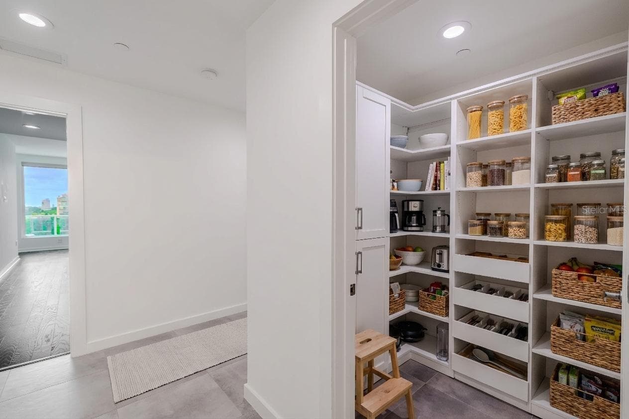 Spacious walk-in pantry with custom built-in shelving, ample storage, and pull-out drawers for easy organization. Clean white cabinetry and adjustable shelves provide both functionality and a polished, modern look. - 920 N OSCEOLA AVE #703, CLEARWATER
