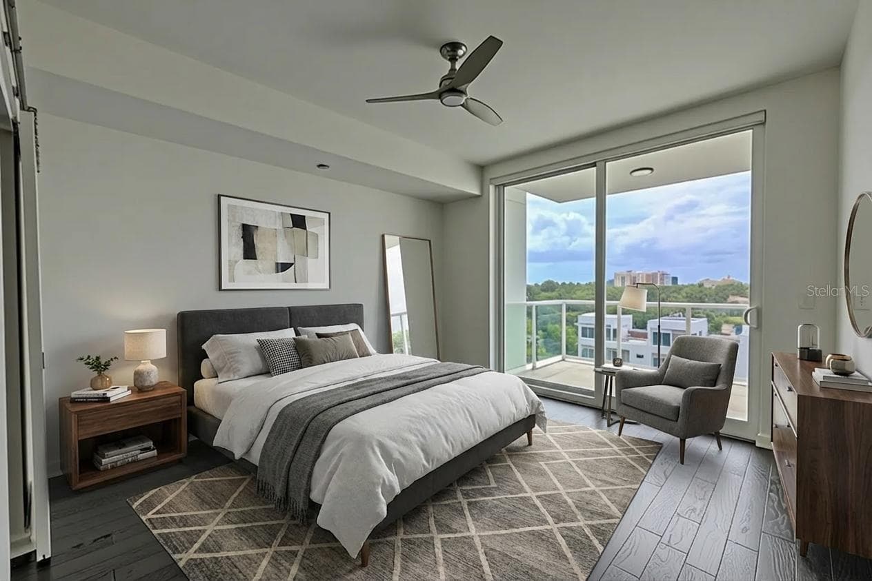 Bedroom 3 is an open and uplifting space, with rich hardwood flooring, crisp white walls, and floor-to-ceiling sliding glass doors that open to a private balcony with lush city and water views. The room is light-filled and airy, complemented by a sleek ceiling fan and modern architectural lines. The en-suite bath and walk-in closet create a comfortable, private suite perfect for guests or extended family. Its direct access to the balcony makes it an inviting space to start or end the day with a view. - 920 N OSCEOLA AVE #703, CLEARWATER