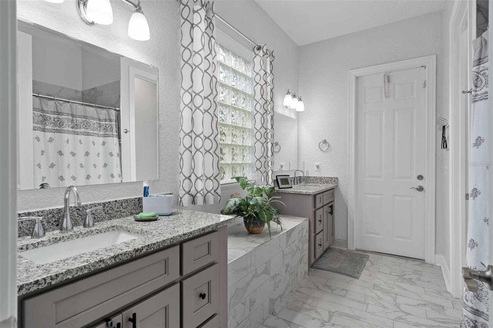 Downstairs Primary Bath fully upgraded with all new his/hers vanities and custom floor tile. Also has a door leading to the rear of the home. - 9057 BALMORAL MEWS SQ, WINDERMERE