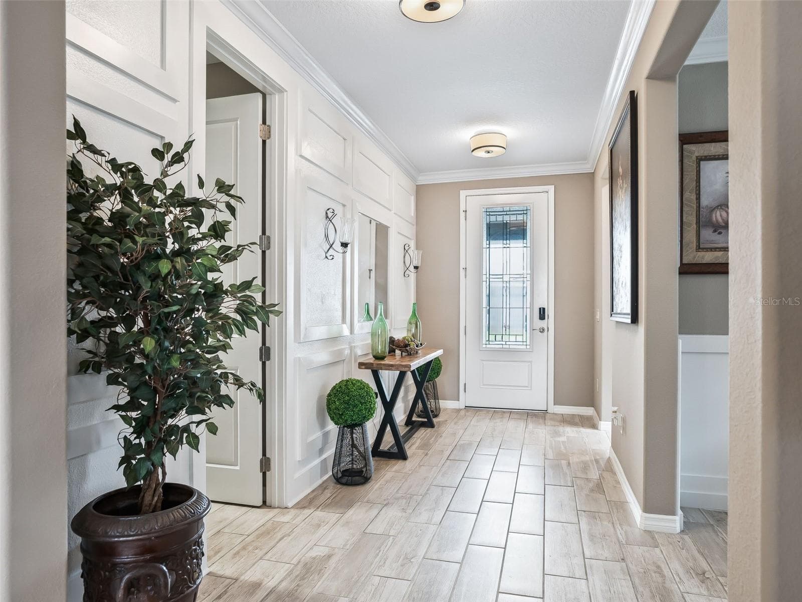 Spacious entrance with architectural details, wood looking ceramic tile and crown molding - 5662 NW 40TH LOOP, OCALA