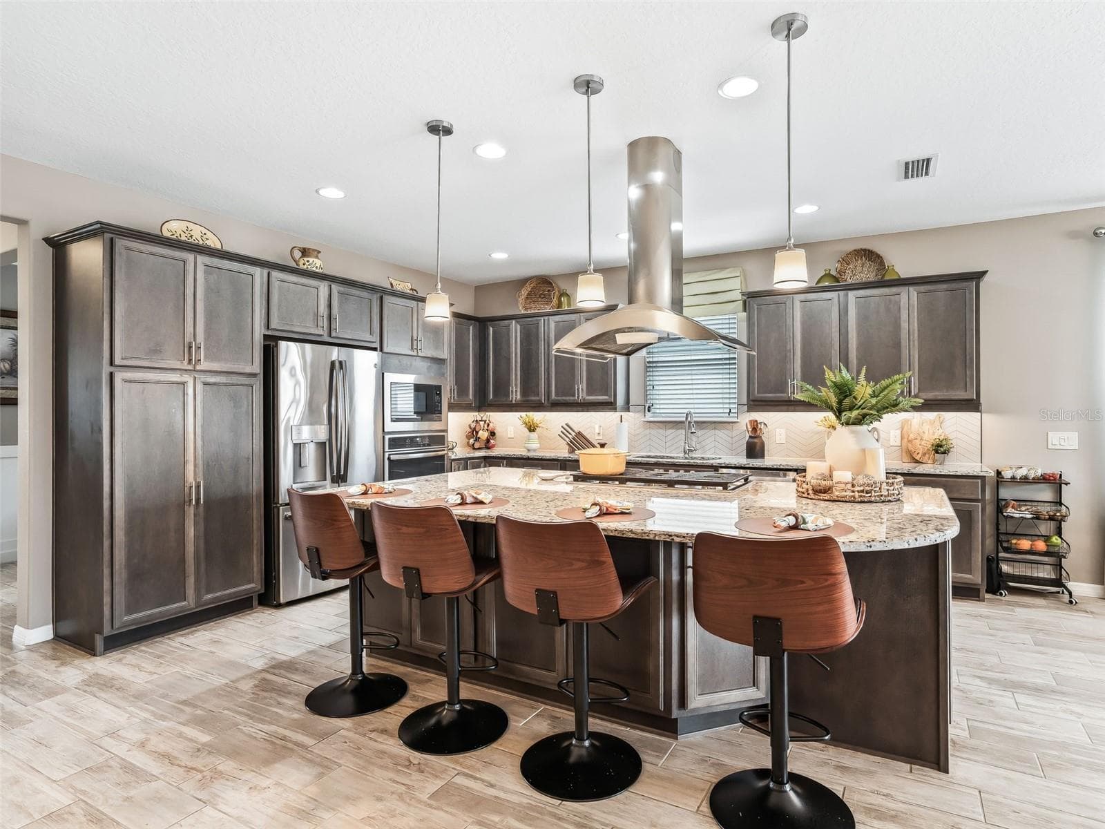 Beautiful wood cabinetry with crown molding, under cabinet lighting, granite countertops, herringbone backsplash and GE Profile stainless steel appliances. Notice the additional cabinetry on the back side of the island! - 5662 NW 40TH LOOP, OCALA