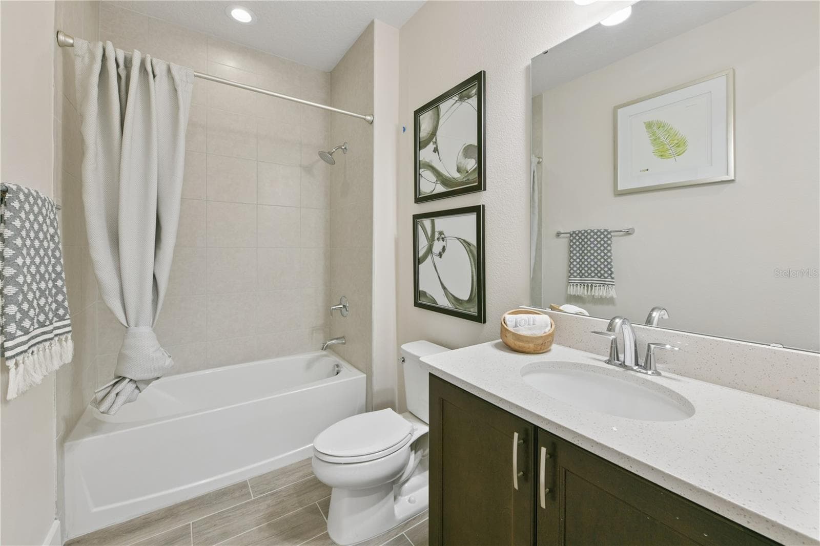 Full bathroom between the two secondary bedrooms at the front of the home highlighted with a tub and quartz vanity - 2418 PARK RIDGE ST, APOPKA
