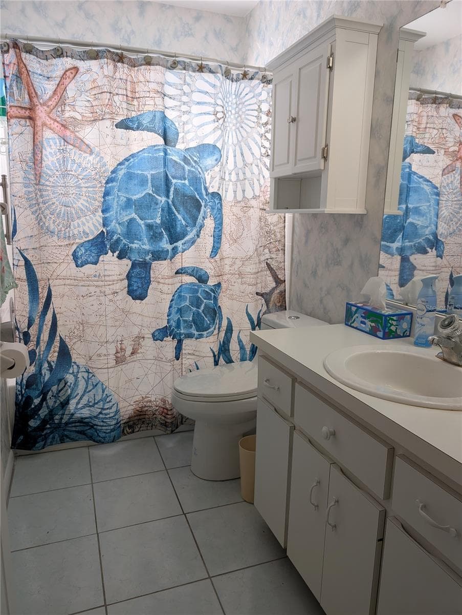 Main bath features white vanity, comfort height commode, tile flooring, medicine chest and a modified tub. - 9204 36TH WAY N #6, PINELLAS PARK