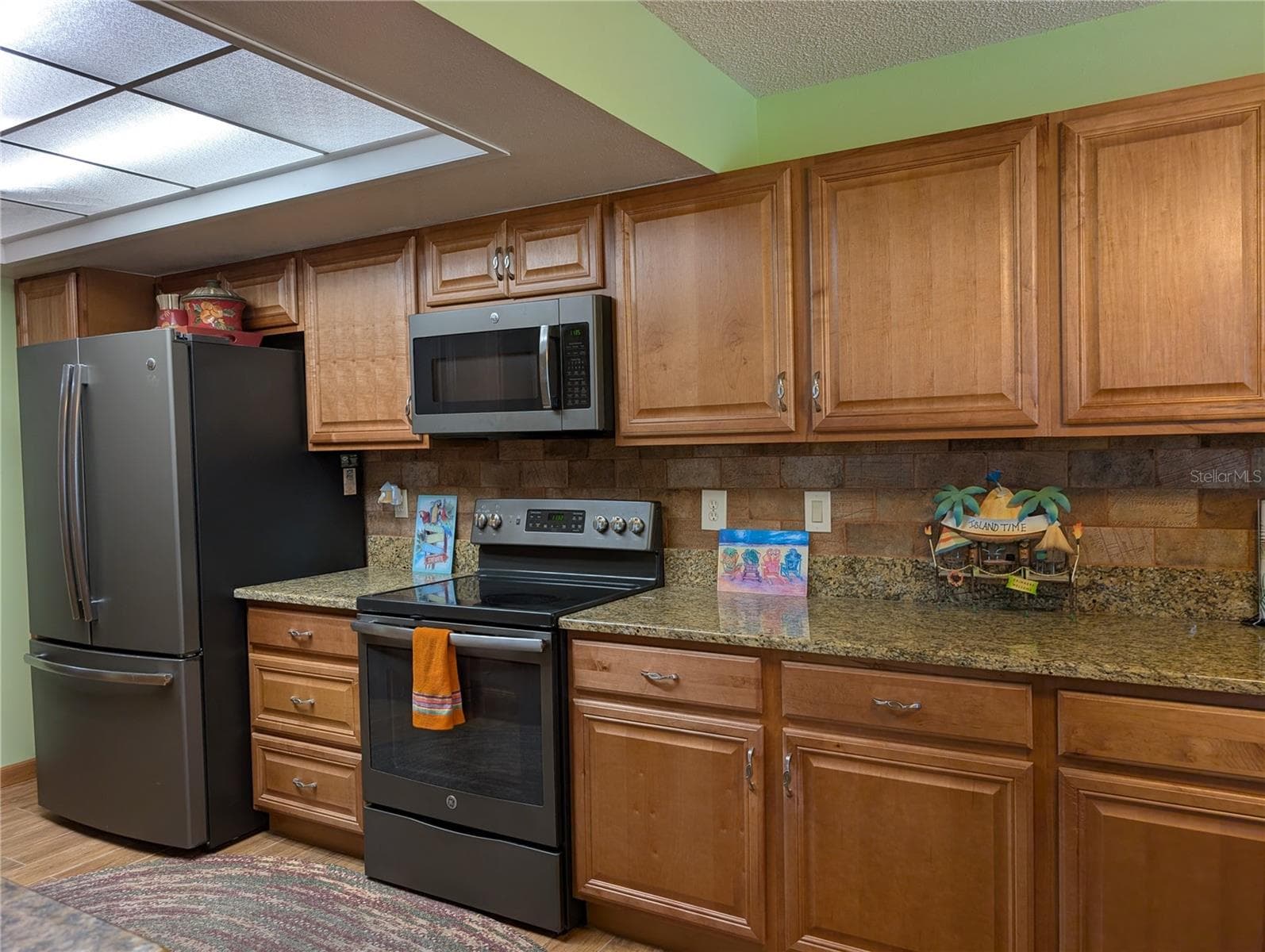 Kitchen appliances include French door frig w/ice maker, glass top range and microwave hood.  Very neutral decor of Honey Oak cabinetry w/brushed nickel hardware, granite countertop and rustic tile backsplash. - 9204 36TH WAY N #6, PINELLAS PARK