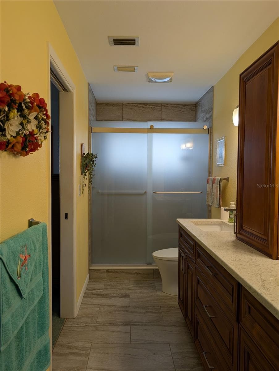 View from interior laundry room into primary bath.  Other notable features include: ceiling vent, walk-in tile shower w/glass doors and comfort height commode. - 9204 36TH WAY N #6, PINELLAS PARK