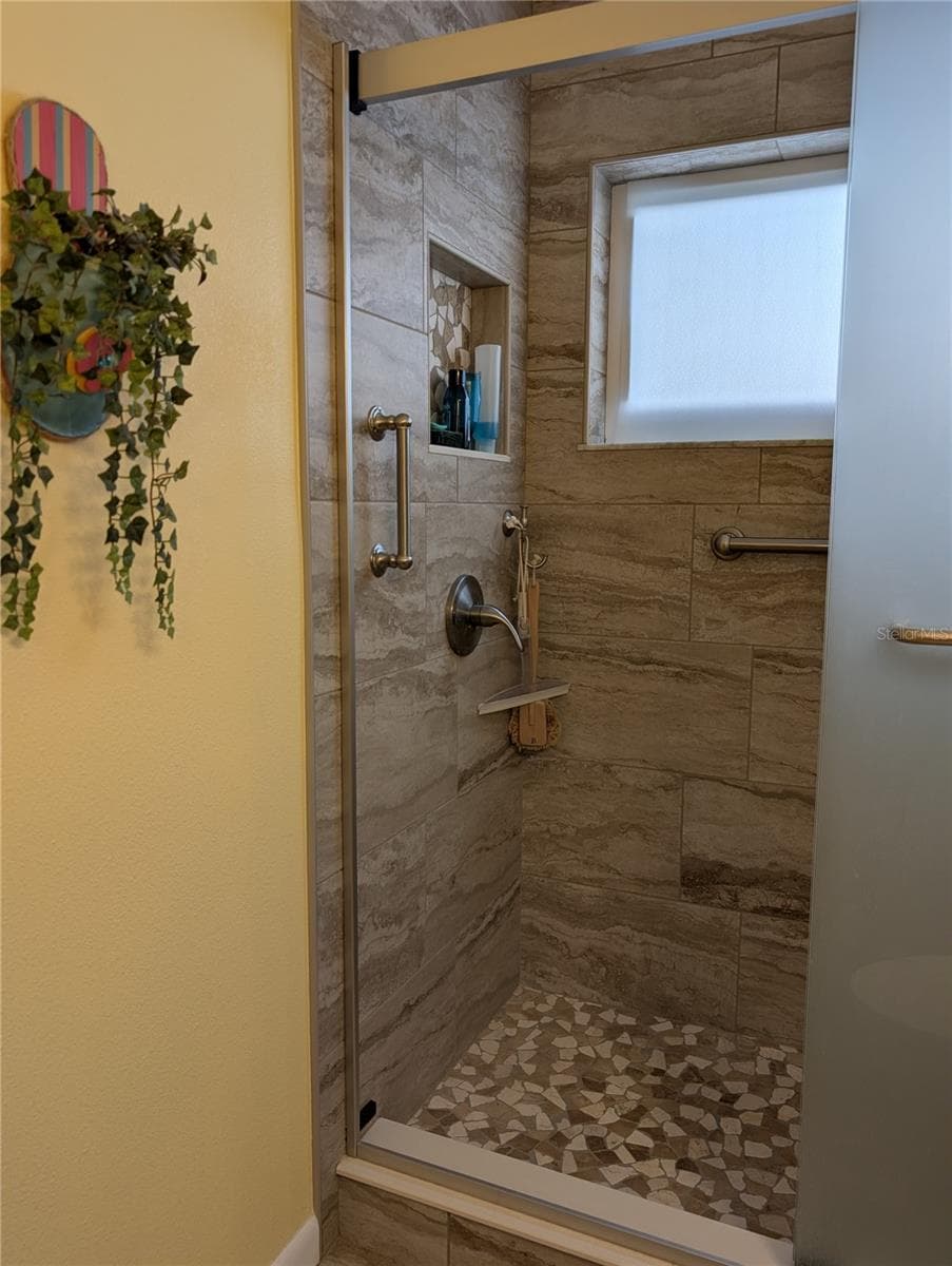 View of stunning tiled shower with brushed nickel hardware and grab bars. Window provides natural light and airflow. - 9204 36TH WAY N #6, PINELLAS PARK