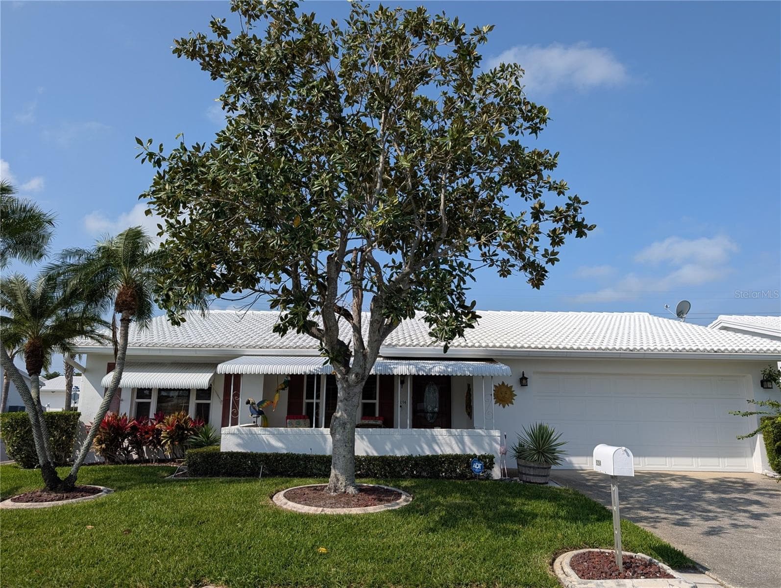 Landscaping is edged with cement curbing.  Exterior features also include gutters/downspouts, tile roof (2002), IMPACT windows (2009) and lawn/irrigation system (maintained by association). Oversized 2 car garage has updated electric panel w/whole house surge protector, Rheem hot water (2020), reinforced garage door, side man door and attic w/pull down ladder. - 9204 36TH WAY N #6, PINELLAS PARK