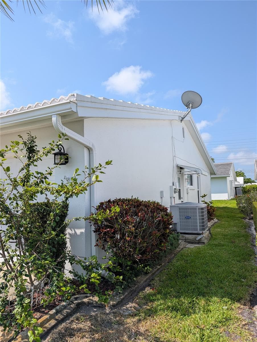 Side of home has 3 ton Carrier HVAC system (2018) and side garage door entry.  Satellite dish is not in use. - 9204 36TH WAY N #6, PINELLAS PARK
