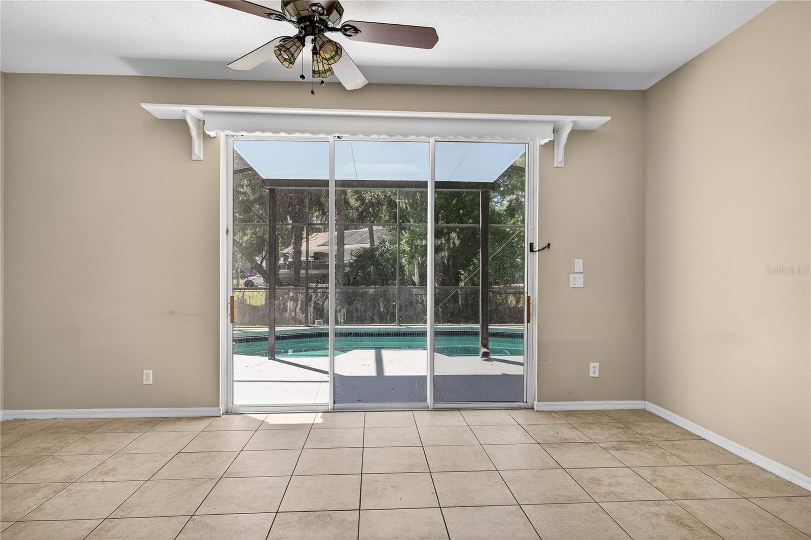 The spacious Family Room is a highlight, featuring glass sliders that seamlessly connect the interior to the inviting outdoor pool area, creating a perfect blend of indoor and outdoor living. - 28931 BEAUCLAIRE DR, TAVARES