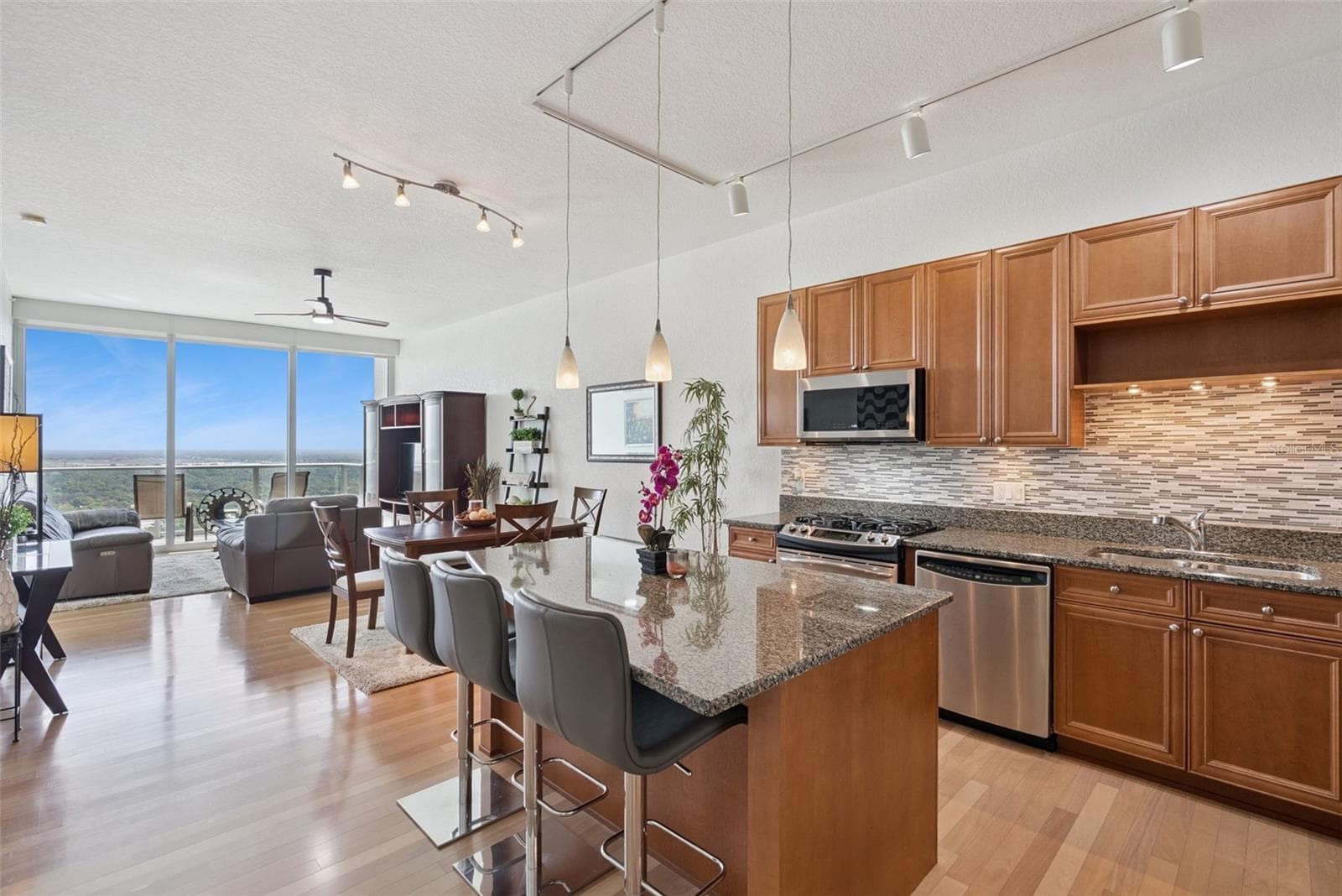 Kitchen features granite countertops, wood cabinetry, a modern backsplash, under-cabinet lighting, and a breakfast bar - 150 E ROBINSON ST #2709, ORLANDO