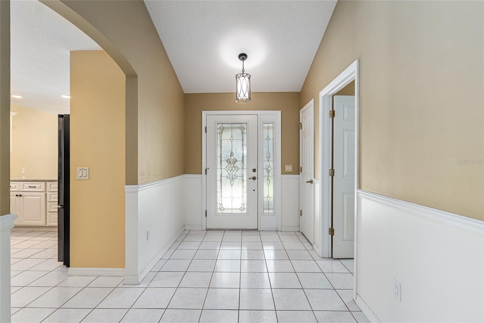 Foyer Reverse View: Entry hallway showcases high ceilings, classic wainscoting detail, and an open flow into the main living areas. - 110 CHULA VISTA AVE, LADY LAKE